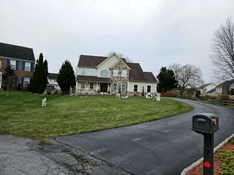 A two-story home set back behind a large lawn along a curving driveway